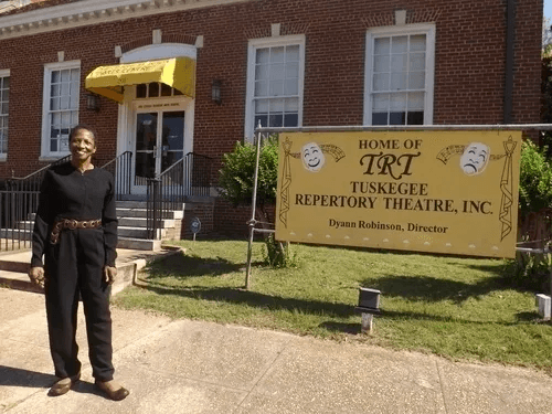Dyann Robinson outside the Jessie Clinton Arts Centre beside the Tuskegee Repertory Theatre sign